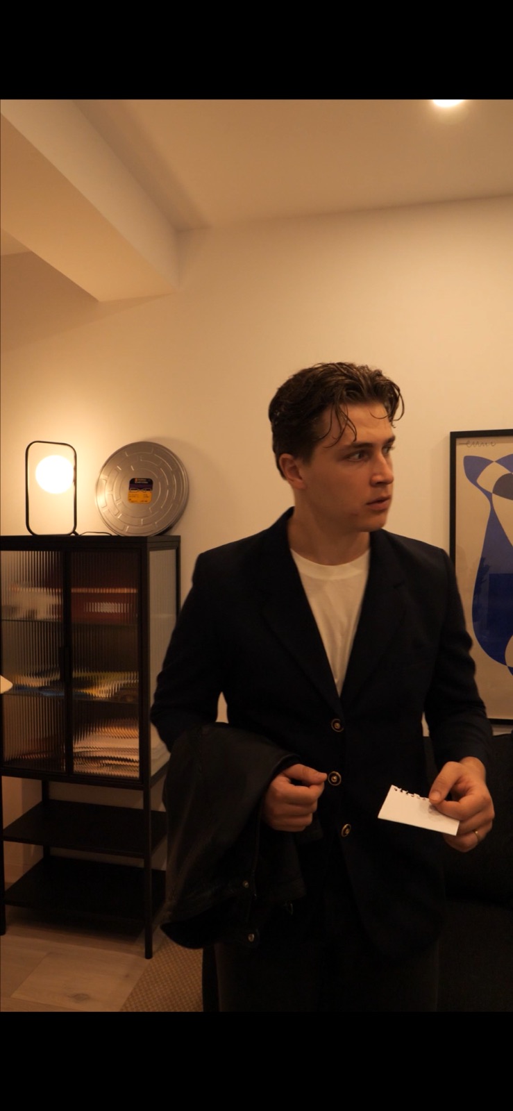 In a dark jacket, holding a card