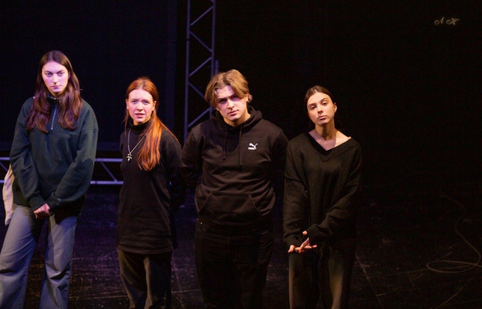Four performers standing under a lighting truss