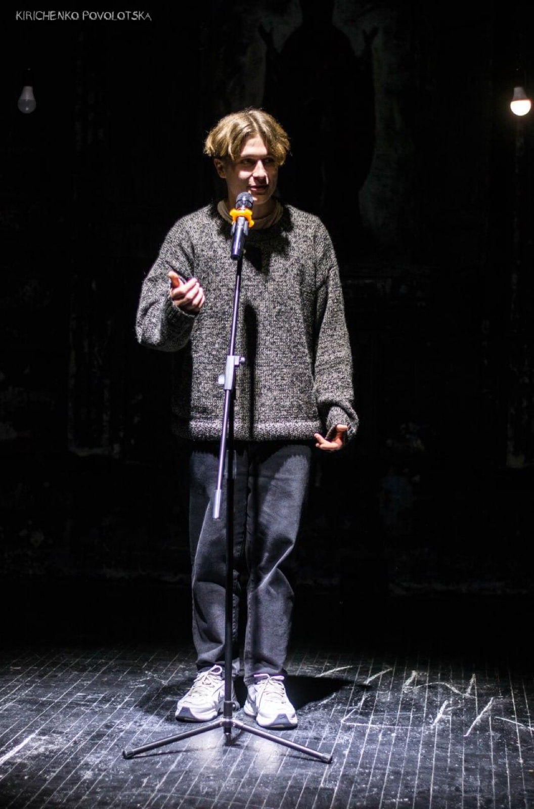 Speaking at a microphone in a single shaft of light, Witnesses
