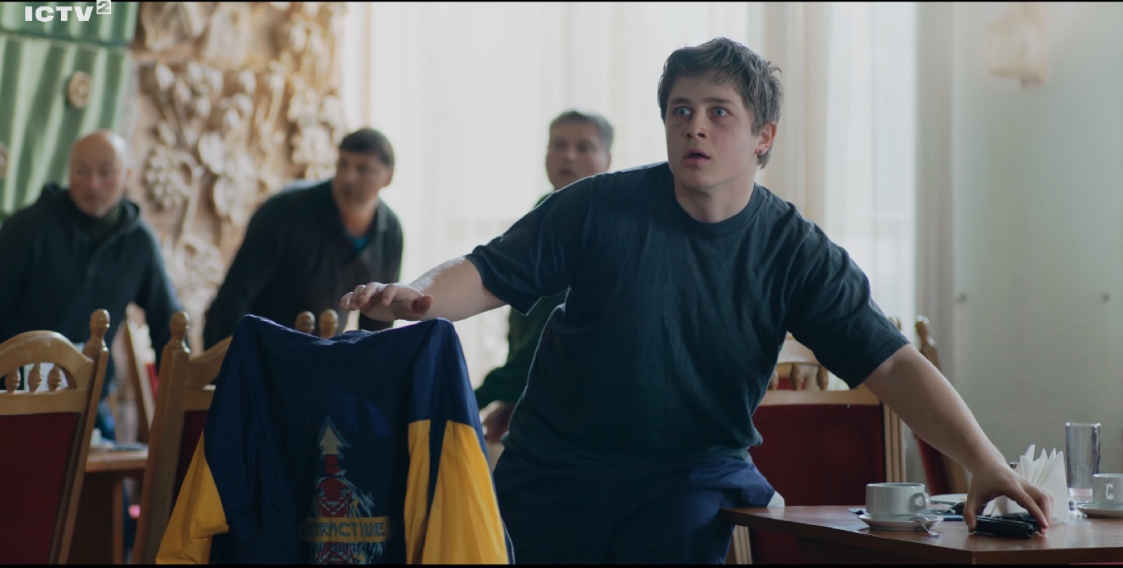 Holding up a jacket in a crowded room, television still