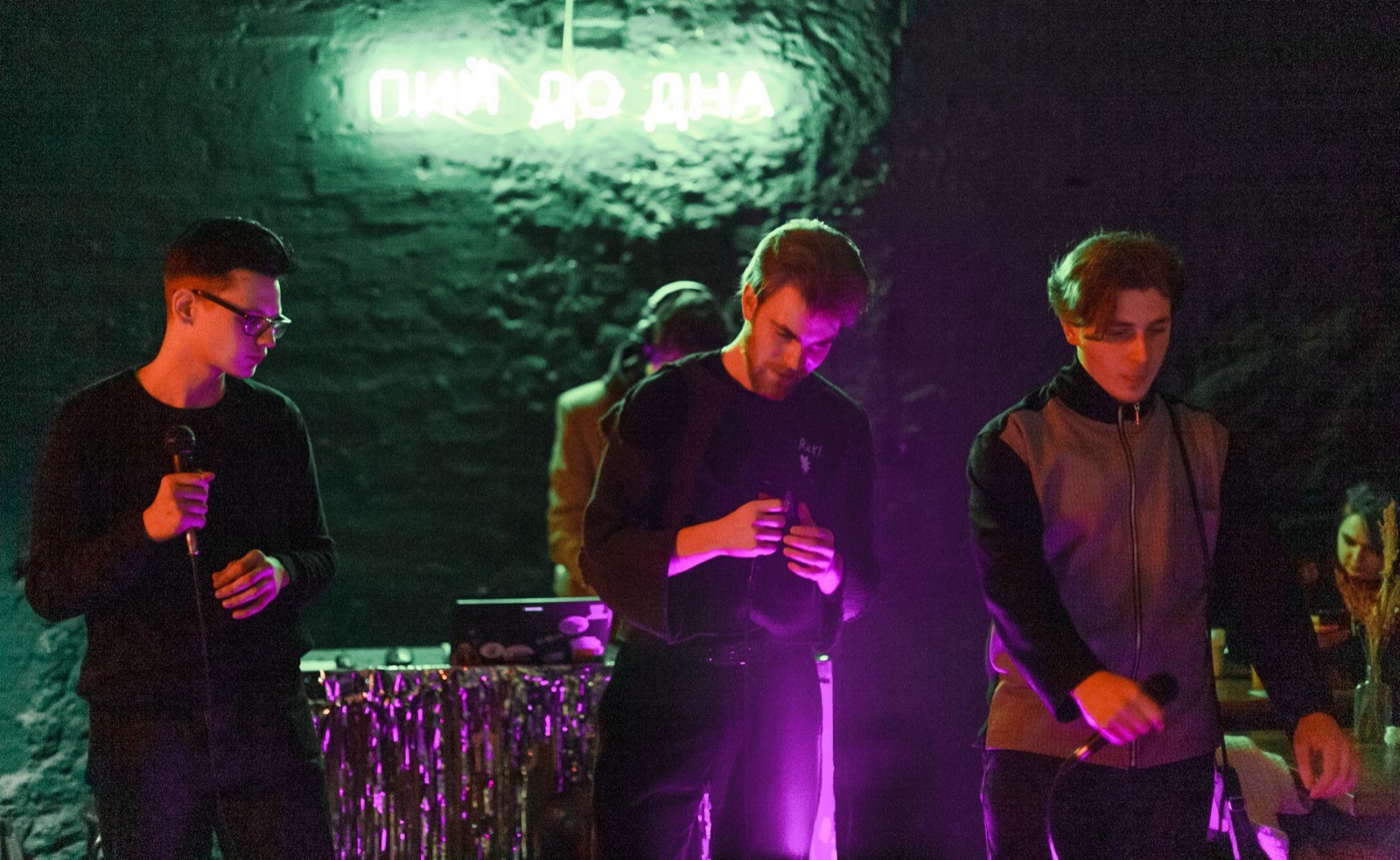 The band performing under a neon sign